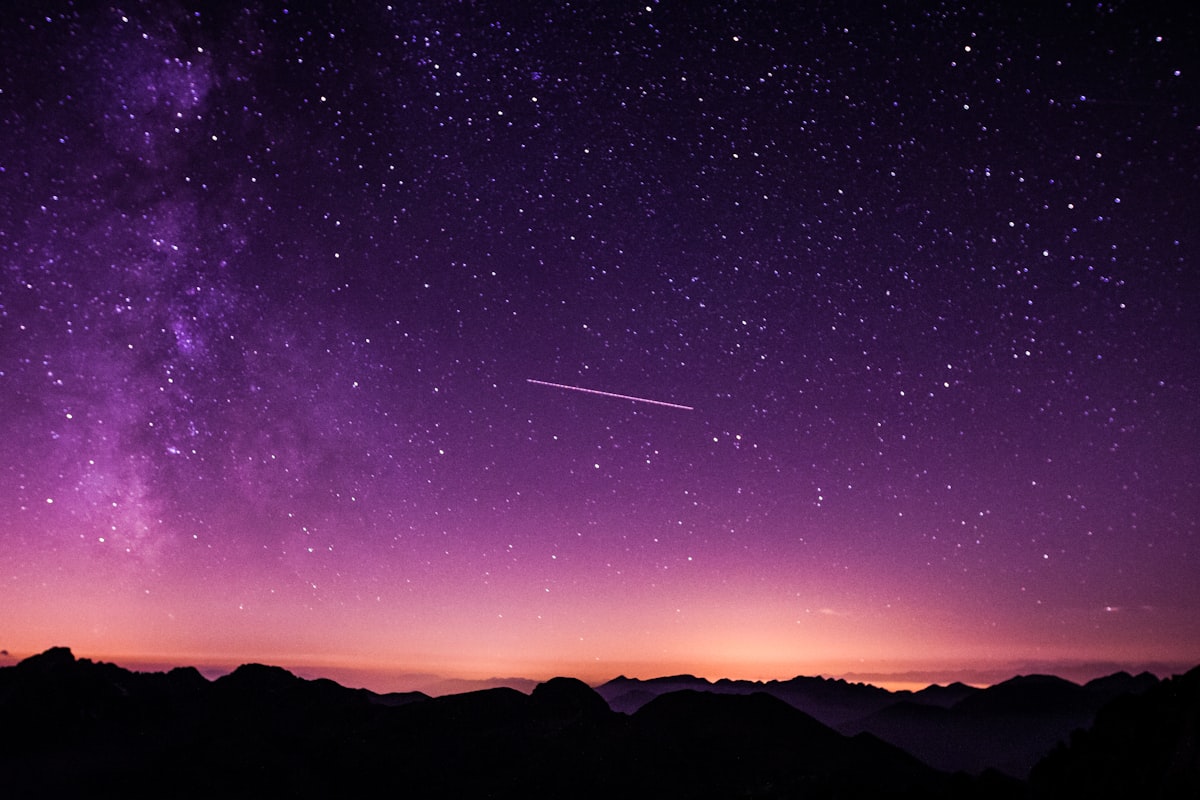 Night sky with visible satellite trails over a rural landscape